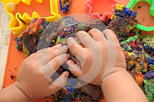 Hands of child playing multicolored kinetic sand. children activity game toy for model forming craft and sculpture art