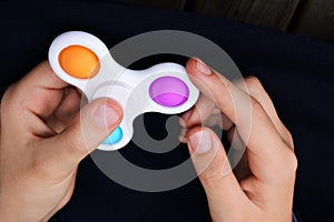 Hands of a child playing with pop it fidget spinner toy