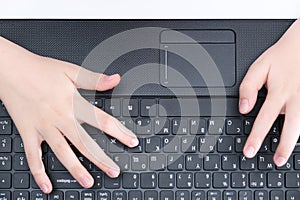 Hands of a child, schoolboy typing text, messages on a laptop keyboard, top view