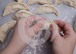 The hands of a child who learns to make dumplings with potatoes. photo
