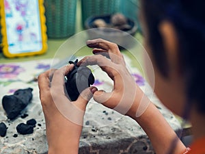 Hands of a child who sculpts with black clay