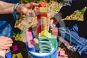 Hands of children playing with colored blocks on a sunny summer day