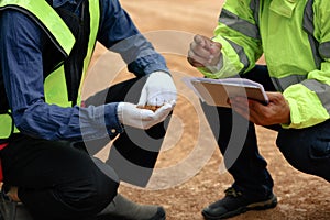 Hands of civil engineers touching and inspecting laterite soil for construction improvement base road work. Engineer Construction