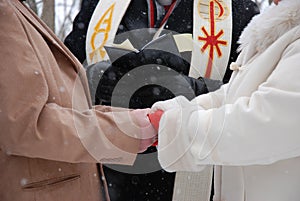 Hands clasped at outdoor winter wedding ceremony