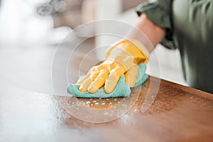 Hands, cleaning and bacteria on a wooden table for hygiene, disinfection or to sanitize a surface in a home. Gloves