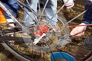 Hands cleaning muddy bicycle spokes