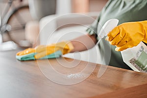 Hands, cleaning and spray on a wooden table for hygiene, disinfection or to sanitize a surface in a home. Gloves