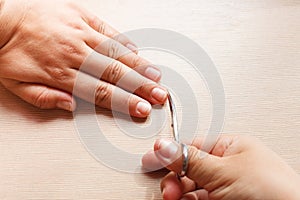 Hands close-up, a girl doing a manicure to herself, nail scissors.