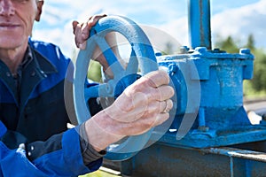 Hands close-up of senior manual worker turning cut-off valve