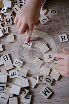 hands close-up, small child 3 years old plays wooden alphabet blocks, makes up words from letters, dyslexia awareness, learning