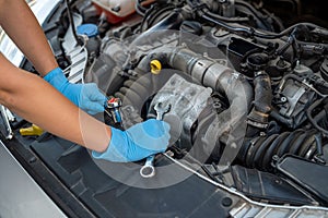hands close up of a smiling young female mechanic performing diagnostics on a car