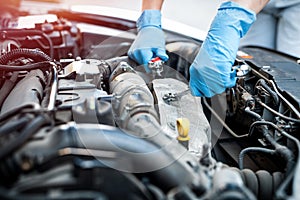 hands close up of a smiling young female mechanic performing diagnostics on a car