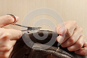 Hands of clothier with a pair of scissors cut strong cloth close up