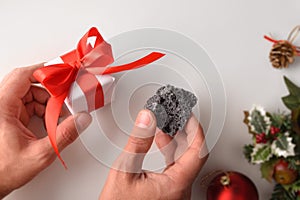 Hands with coal and christmas gift reward concept for behavior