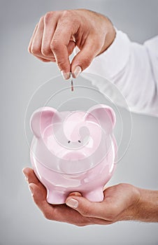 Hands, coin in piggy bank and saving for future, person has financial freedom or budget with money on grey background