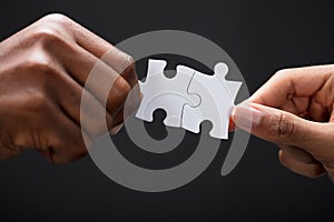 Hands Combining White Puzzle Pieces