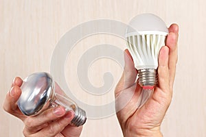 Hands compared incandescent bulb and ecofriendly led lamp
