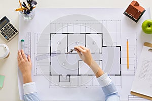 Hands with compass measuring blueprint at office