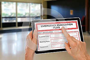 Hands with Computer Tablet and Emergency Evacuation Plan by Doors