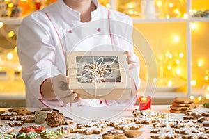 Hands of confectioner showing a box with gingerbread cookies