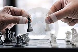 Hands of confident businessman colleagues playing chess game to