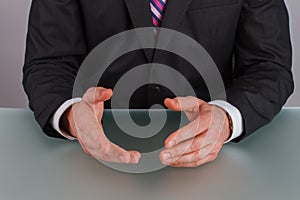 Hands of confident businessman sitting at table.