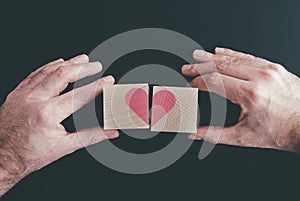 Hands connecting or disconnecting woodenblocks with red heart