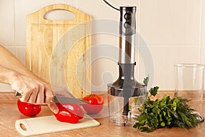 Hands cook cut red peppers on kitchen table