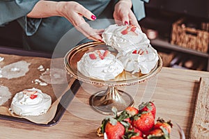 Hands of a cook garnishing meringue desserts, elegant kitchen backdrop. For gourmet food blogs. photo