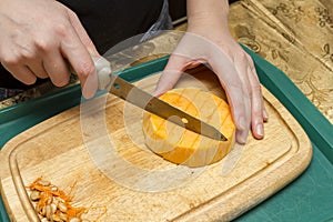 Hands cook with a knife and a pumpkin.