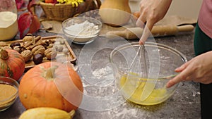 hands cooking pumpkin pie making dough mix eggs and sugar in bowl with whisk