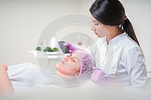 Hands of cosmetologist making ultrasound facial cleaning with special machine