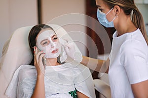 Hands of cosmetology specialist removing white facial mask using brush. Making skin hydrated and face glowing and skin