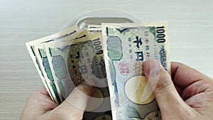 Hands count yen and place them in a tray for change for shopping or business and travel