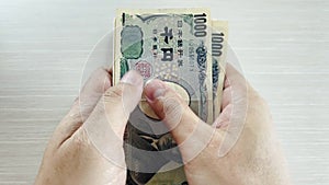 Hands count yen and place them in a tray for change for shopping or business and travel
