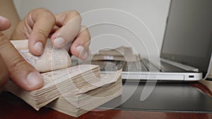 Hands counting a lot of thousands Thai baht banknotes money.