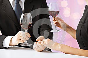 Hands of couple with diamond ring and wine glasses