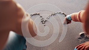 Hands, couple and heart in the sand at the beach for travel, date or together in summer. Relax, vacation and a man and