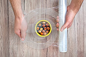 Hands covering the onion in a pot of soil with clear plastic wrap