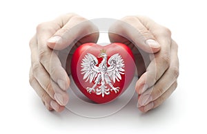 Hands covering Polish coat of arms