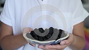 Hands cradle a bowl of ripe blackberries, a bounty of nature s goodness. This image celebrates healthy eating and the