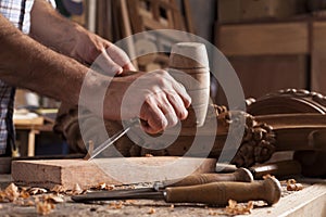 Hands of craftsman carve with a gouge photo