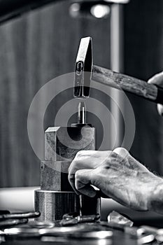 Hands of an craftsman working with the hammer and metal tongues