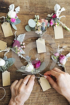 Hands creating boutonnieres with paper tags