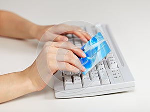 Hands with credit card on computer keyboard