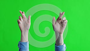 Hands crossed fingers for good luck and victory on a green background. Pray. Green screen