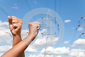 Hands crossed shows fists and power transmission lines against b