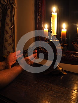 Hands with crucifix and candles in the dark