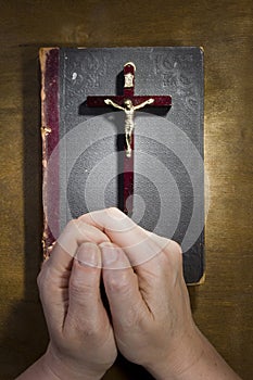 Hands with a crucifix and an old book