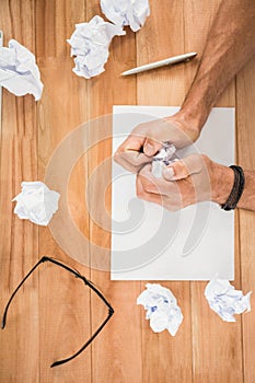 Hands crumpling paper on wooden desk